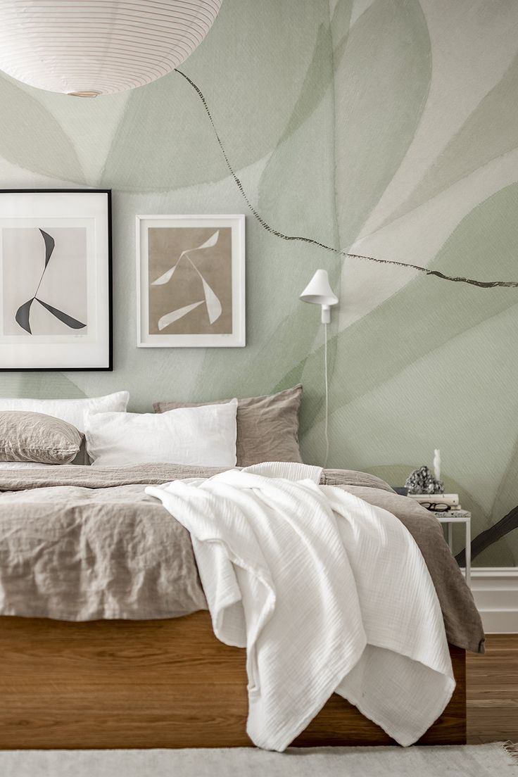 a bedroom with green and white wallpaper, a bed in the foreground and two framed pictures on the wall