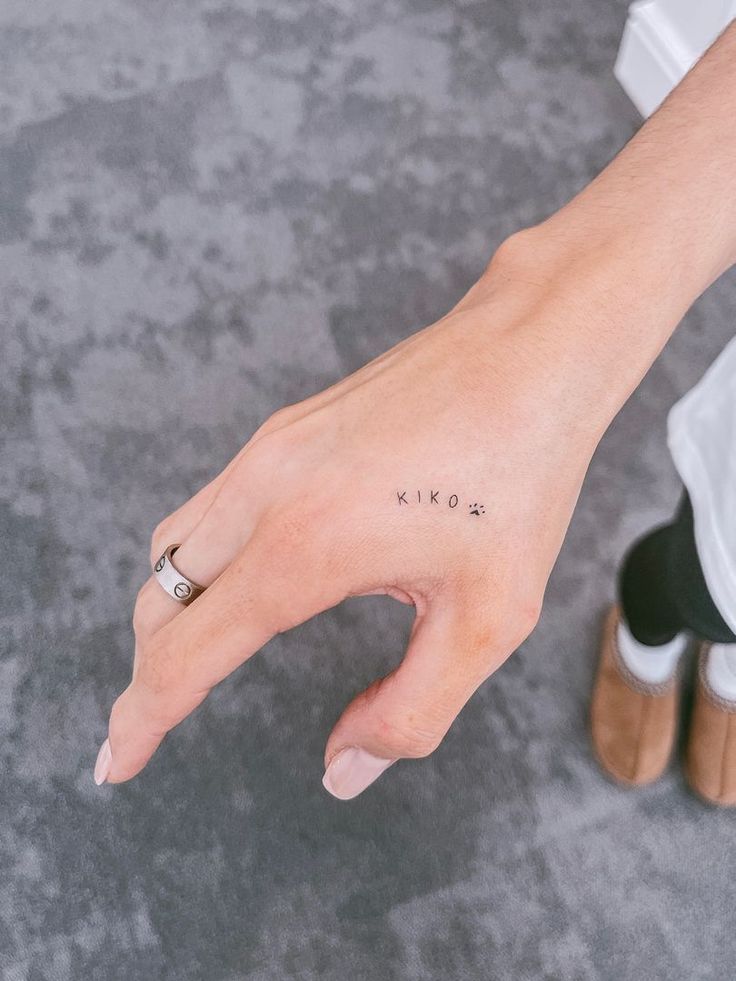 a woman's hand with the word love tattooed on her left thumb and finger