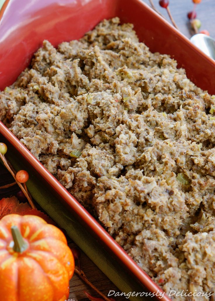 a casserole dish filled with stuffing next to pumpkins and other autumn decorations