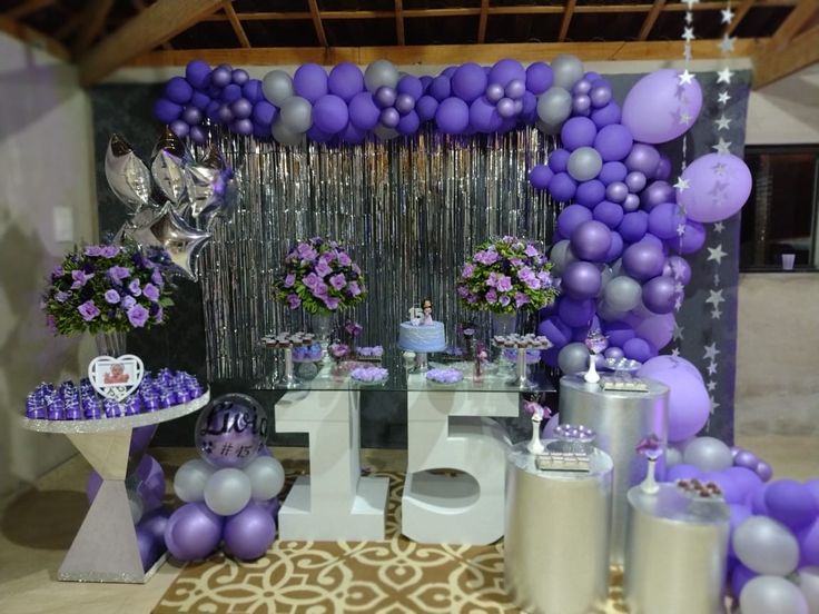 a table topped with lots of purple and silver balloons