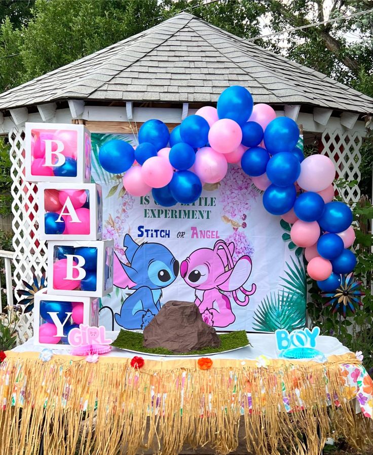 a stitch & angel themed banner is hung behind a table with a DIY volcano placed on top of it. there is a pink & blue balloon arch above the banner & on the sides of the volcano it says “boy, girl”. the table has a table skirt on it & there are boxes on the left side that say “baby”. Lilo Gender Reveal, Stitch Themed Gender Reveal Ideas, Gender Reveal Ideas Anime, Gender Reveal Ideas Hawaiian, Lilo And Angel Gender Reveal Ideas, Gender Reveal Ideas Cartoon Theme, Cartoon Theme Gender Reveal, Angel Or Stitch Gender Reveal, Gender Reveal Ideas Cartoon