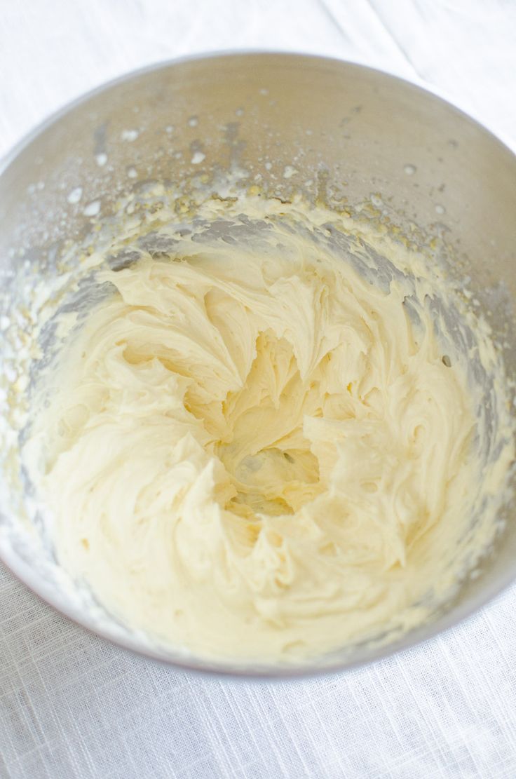 a bowl filled with yellow batter on top of a white tablecloth covered table cloth