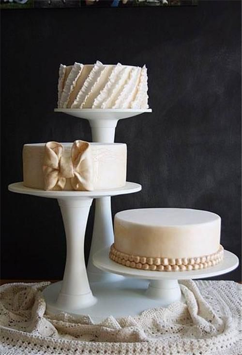 three tiered cake stands on top of a white doily with pearls and bows