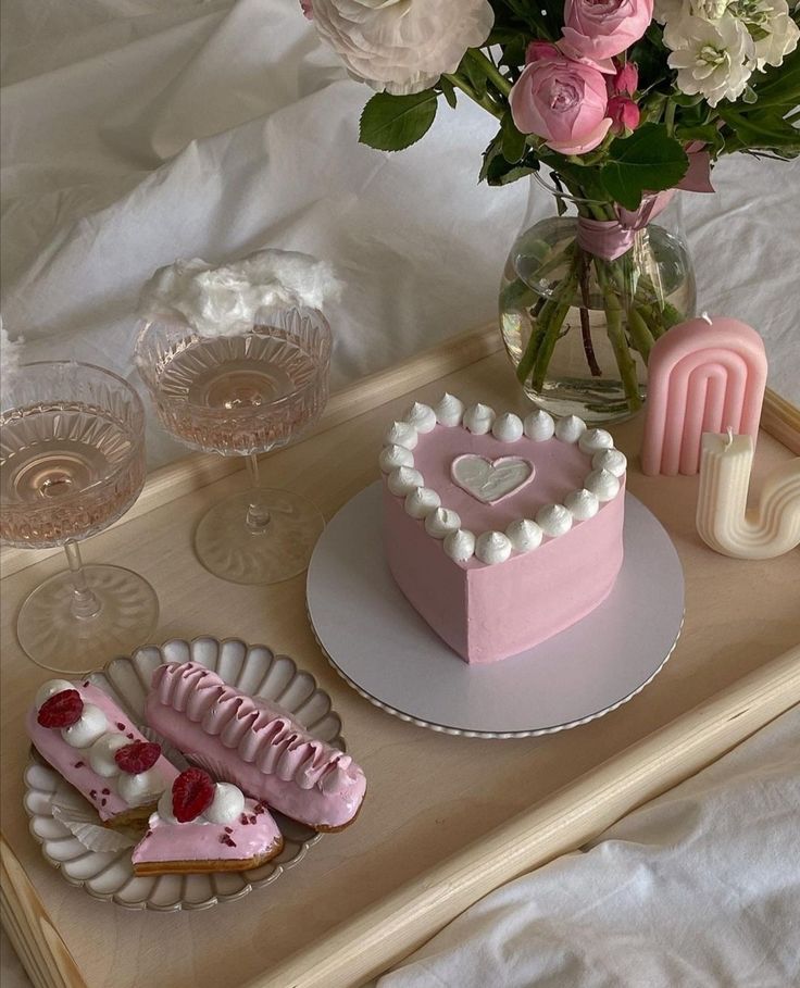 a tray topped with cakes and flowers on top of a bed