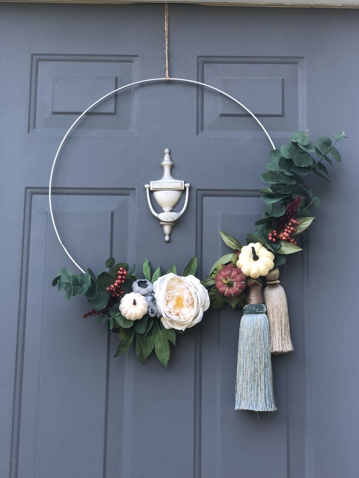 a wreath with flowers and tassels hanging on a door