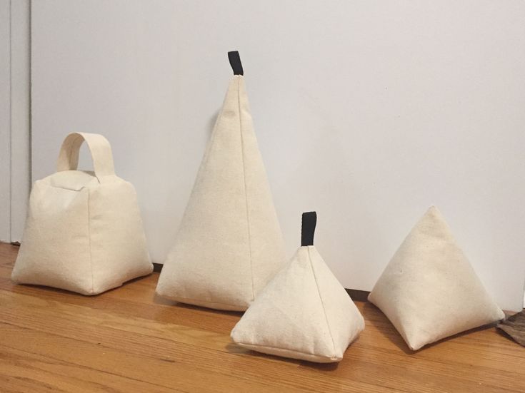 three white bags sitting on top of a wooden floor next to a wall with black handles