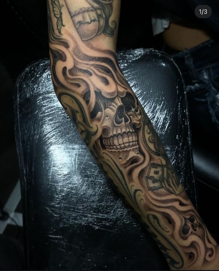 a man's arm with a skull and cross tattoo on the side of it