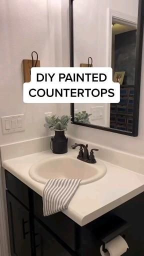 a white sink sitting under a bathroom mirror next to a black cabinet and counter top