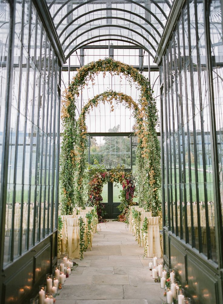 the inside of a greenhouse with candles and greenery on either side of the walkway