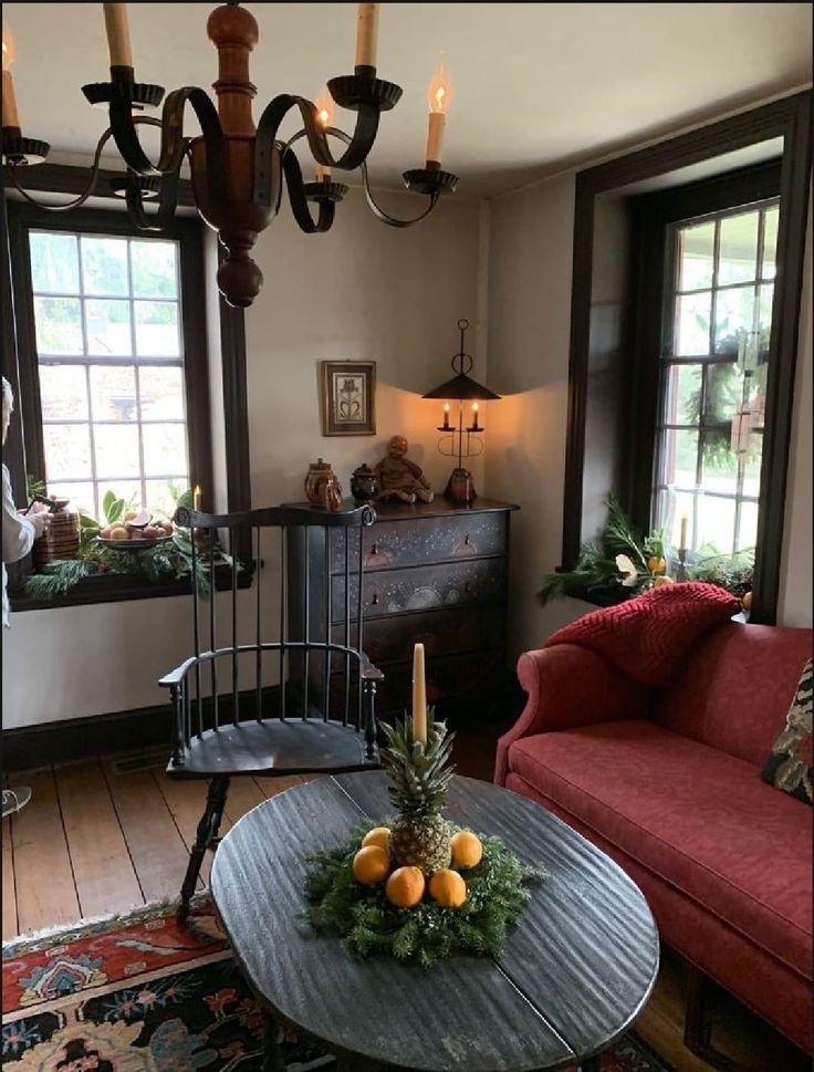 a living room filled with furniture and a chandelier hanging from the ceiling next to two windows