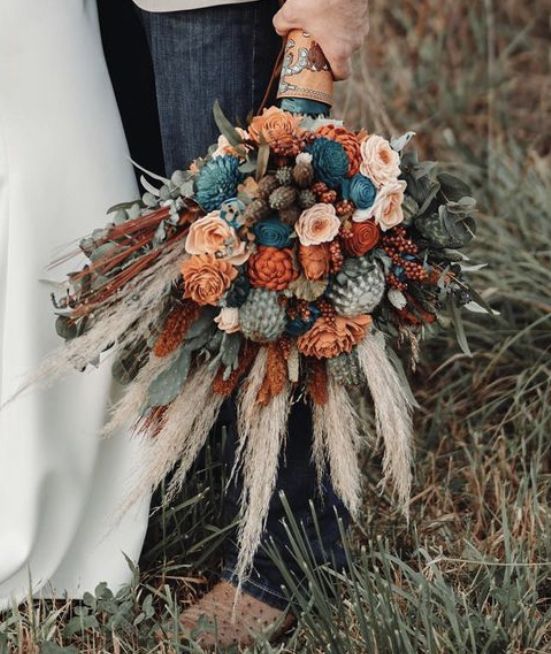 the bride and groom are holding their bouquets in front of each other, with pine cones on them