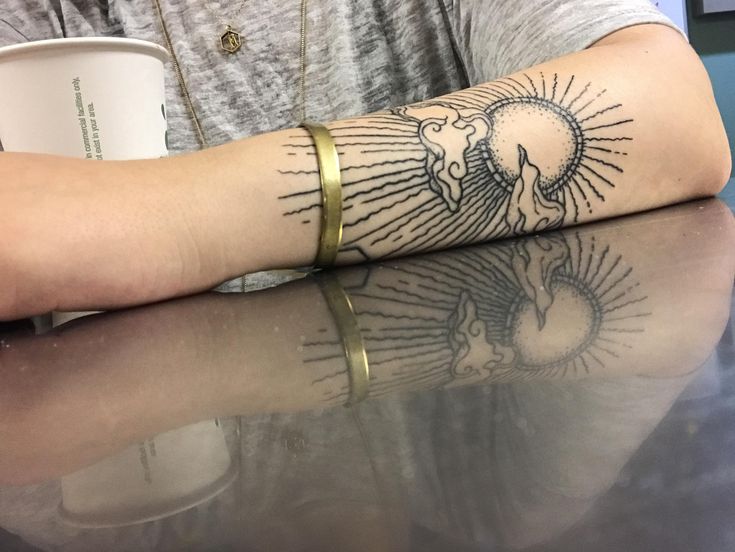 a person sitting at a table with a tattoo on their arm