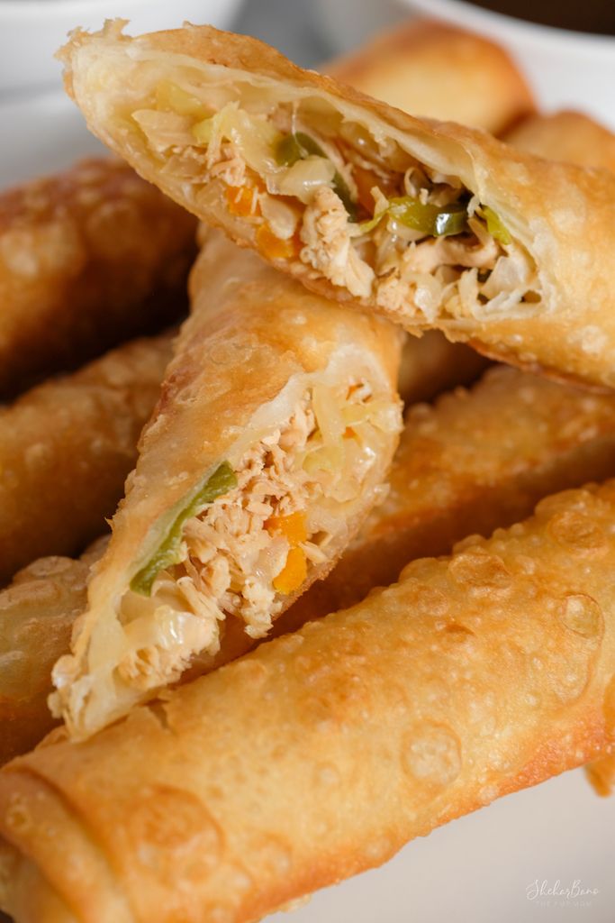 some fried food is stacked on top of each other in a white plate with dipping sauce