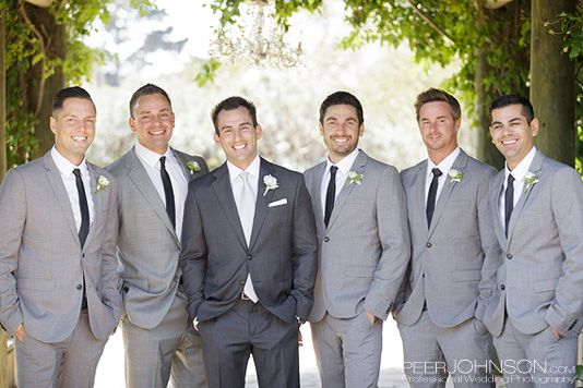 a group of men standing next to each other wearing suits and ties with trees in the background