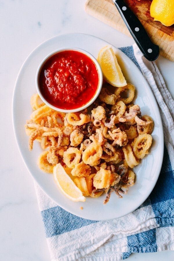 a white plate topped with pasta and sauce next to lemons on a cutting board