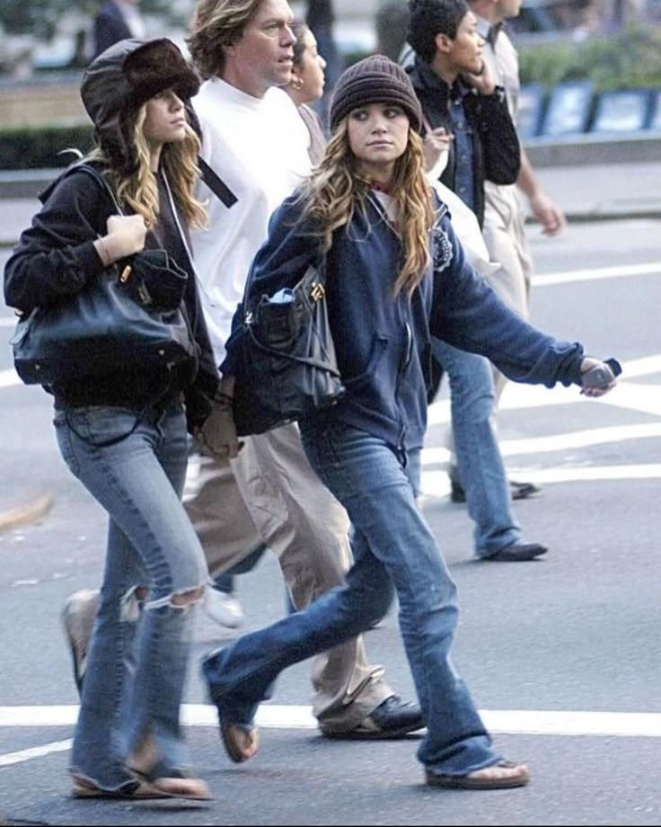 several people walking down the street with one person talking on a cell phone and another standing behind them