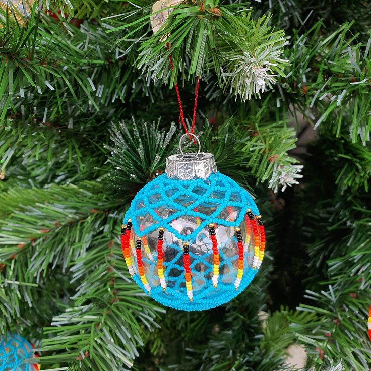 an ornament hanging from a christmas tree decorated with beads and crochet