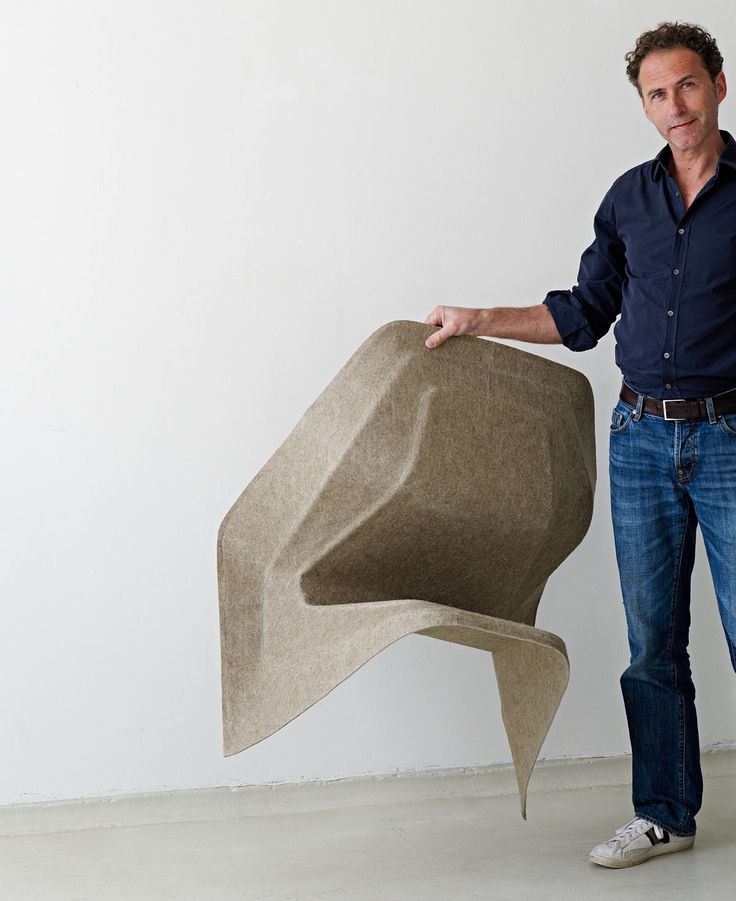 a man standing next to a sculpture made out of concrete and holding it in his hands