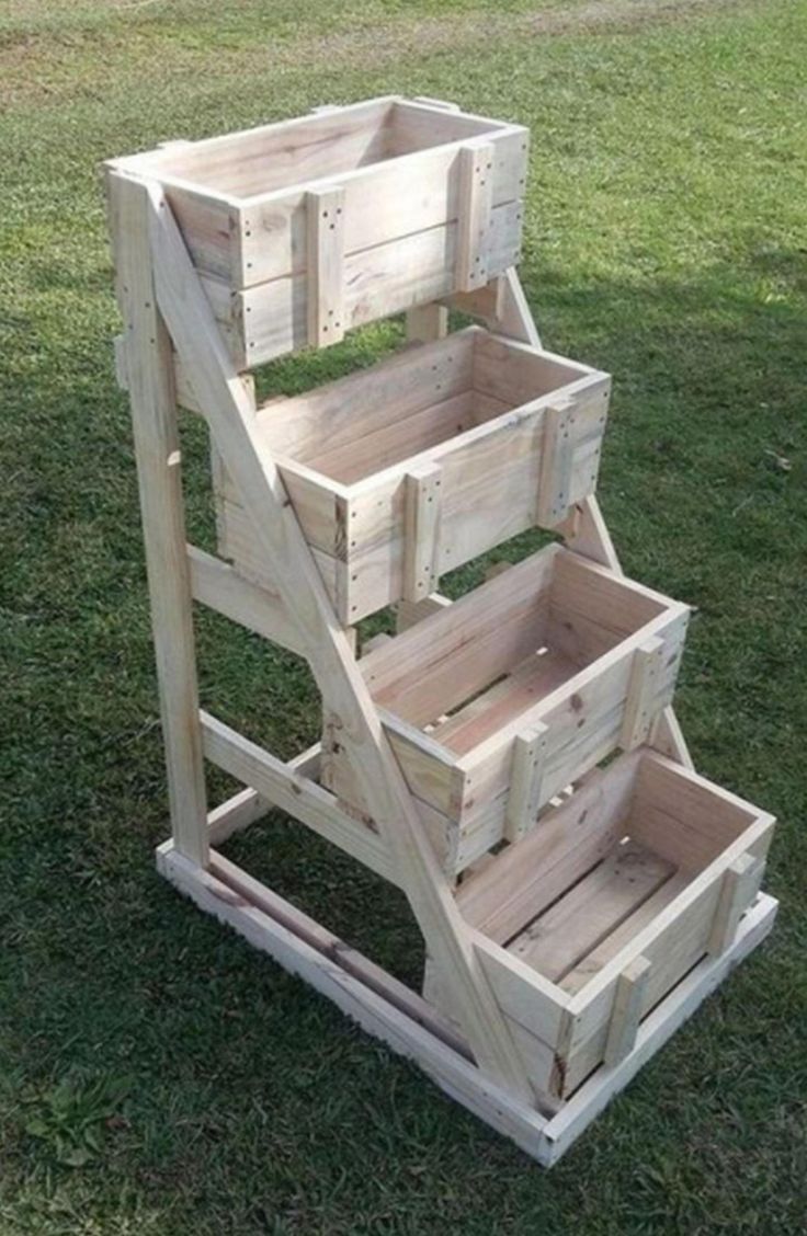 three wooden crates stacked on top of each other in the grass, with one being used as a planter