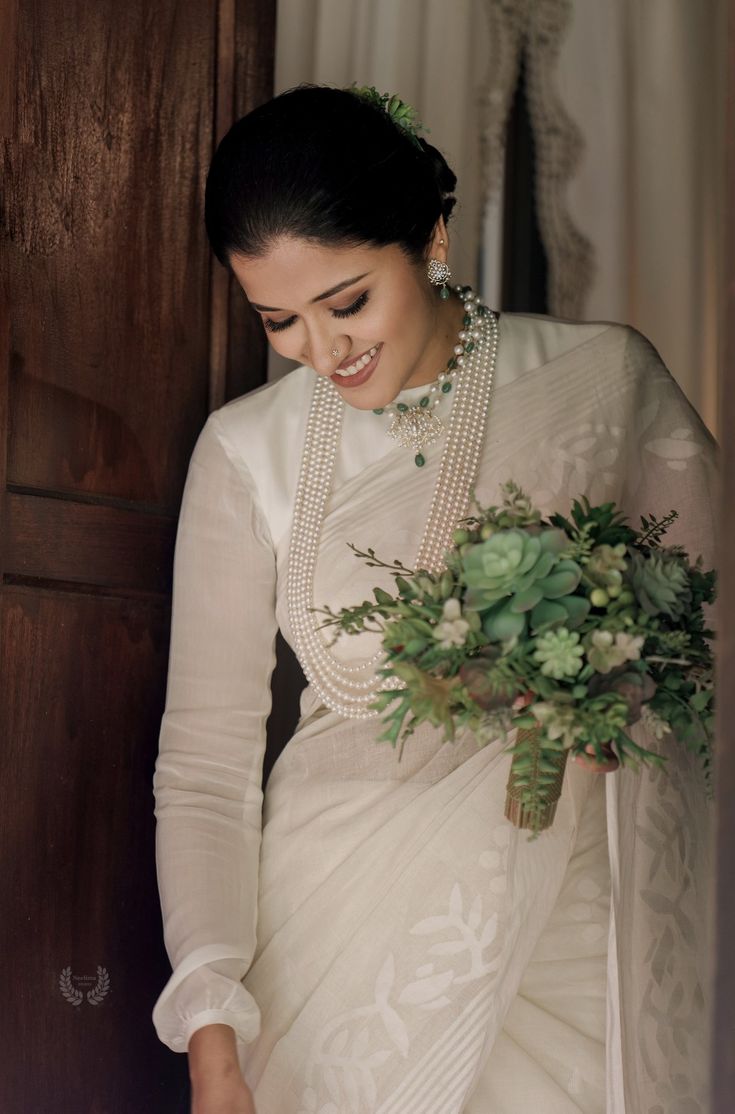 a woman in a white sari holding a bouquet of flowers