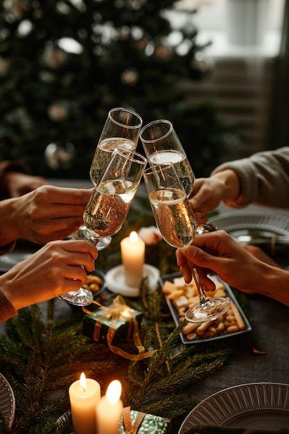 three people toasting with wine glasses in front of a christmas tree and lit candles