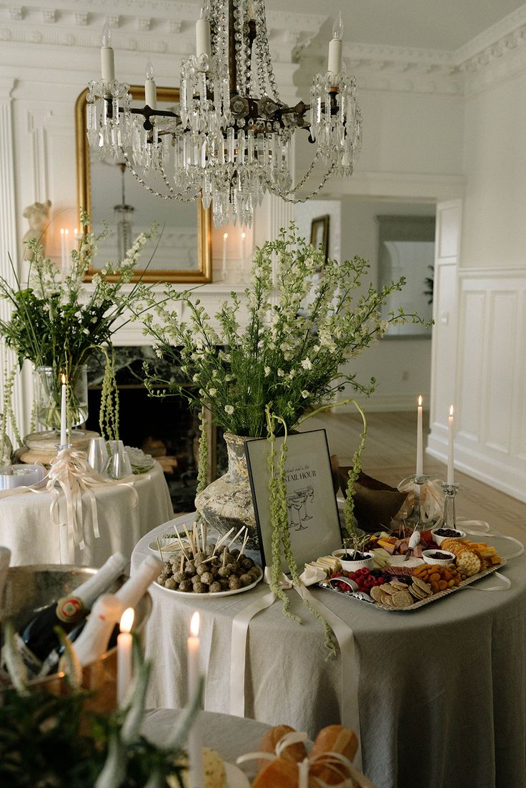 a table topped with lots of food next to a chandelier filled with candles