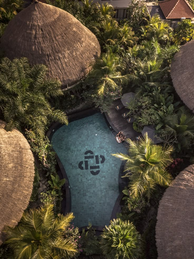 an aerial view of a pool surrounded by palm trees and umbrellas, with the word up written on it