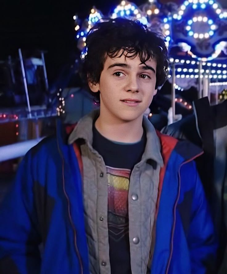 a young man standing in front of a carnival ride