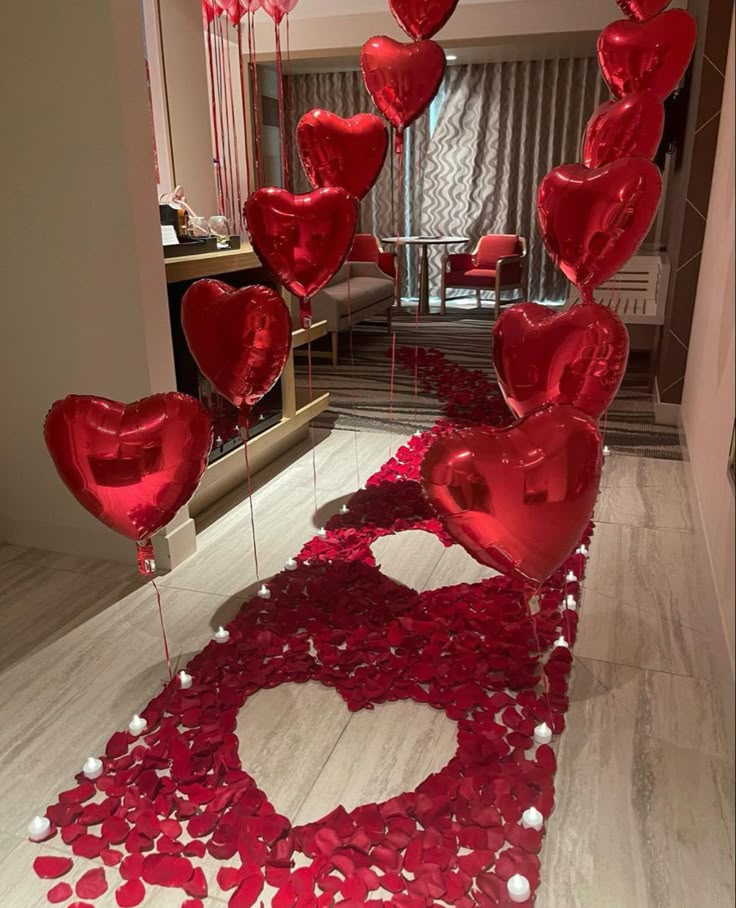 red heart balloons floating in the air on a floor with white and pink confetti