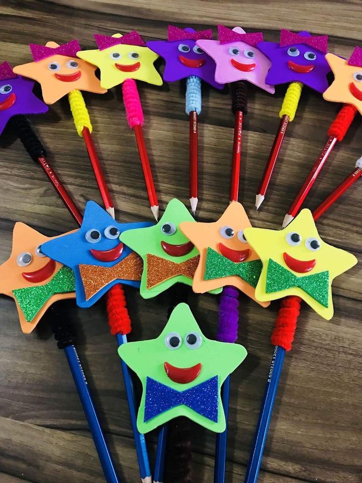 colorful star shaped pencils with different colored faces and eyes on them, lined up in a row