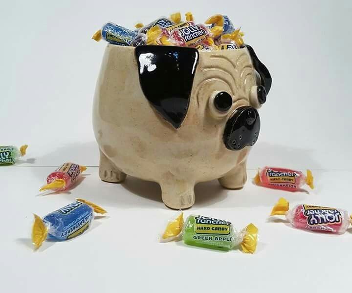 a ceramic dog pot with candy and candies around it on a white table top