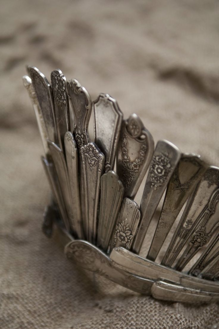 a pile of silver spoons sitting on top of a table next to a quote