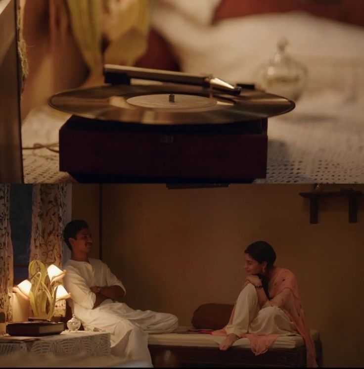 two people sitting on a bed in front of a record player and candle lit candles