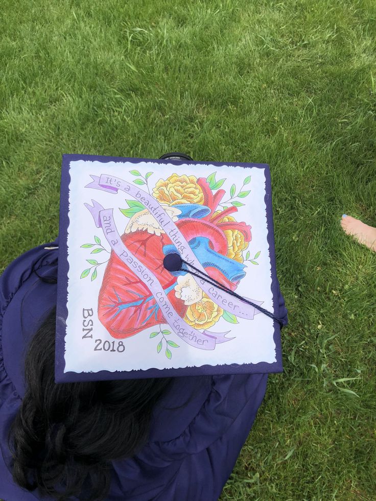 a graduate's cap on top of a blue hat laying in the grass with scissors