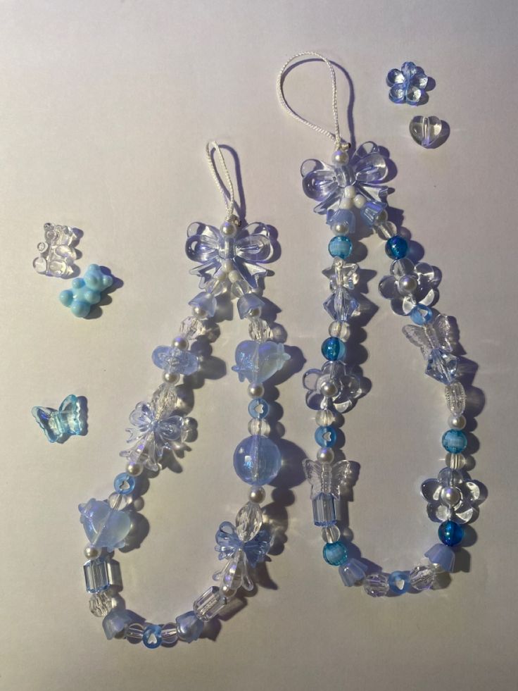 three pieces of jewelry are laying on a white surface with blue beads and butterfly charms