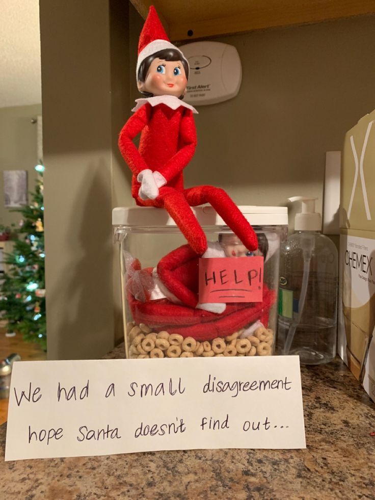 an elf is sitting on top of a jar with cereal in it and a sign that says, we had a small disorganment hope santa doesn't find out