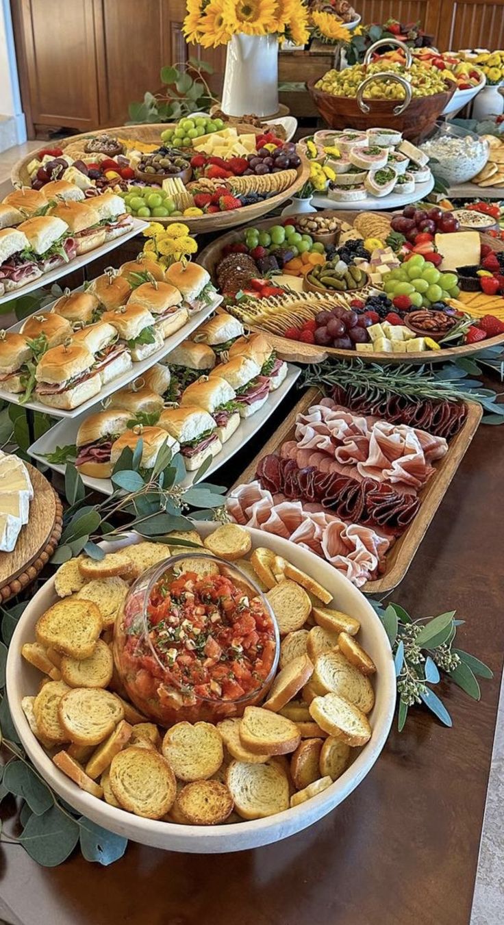 a table filled with lots of different types of sandwiches and appetizers on trays