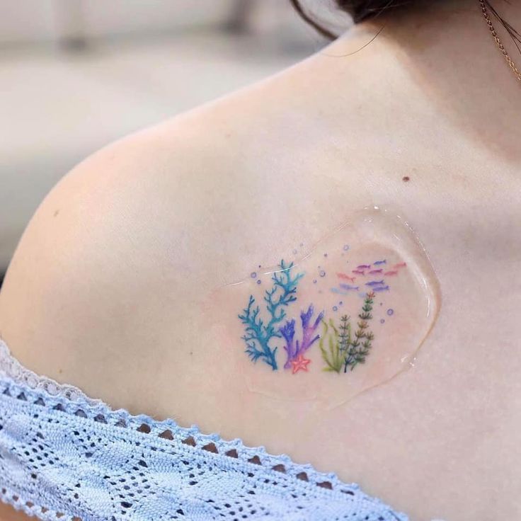 a woman with a tattoo on her shoulder shows off the back of her top half