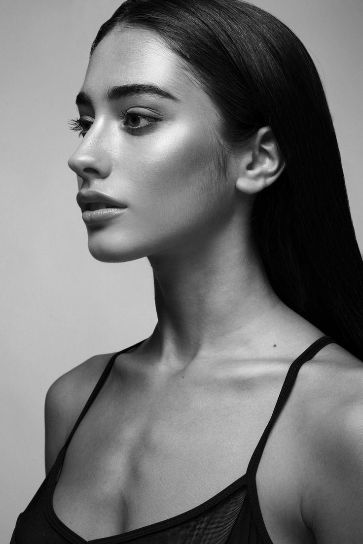 a woman with long hair wearing a tank top and looking off to the side in black and white