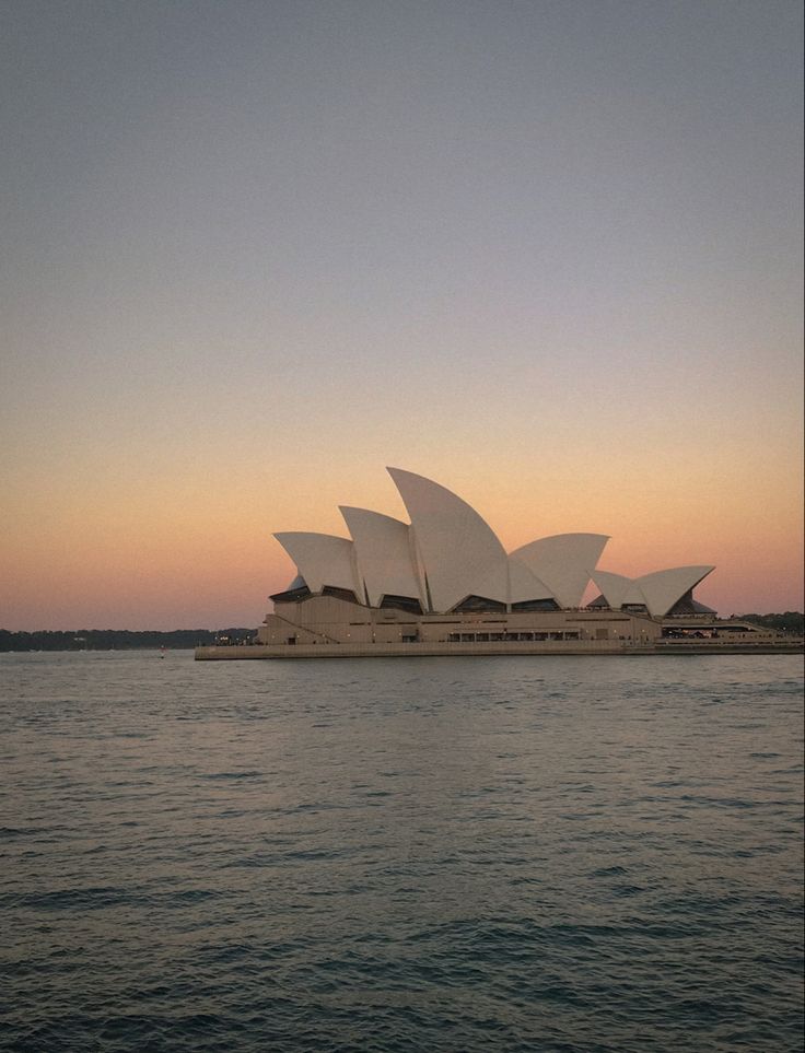 the sydney opera house at sunset as seen from across the water in front of it