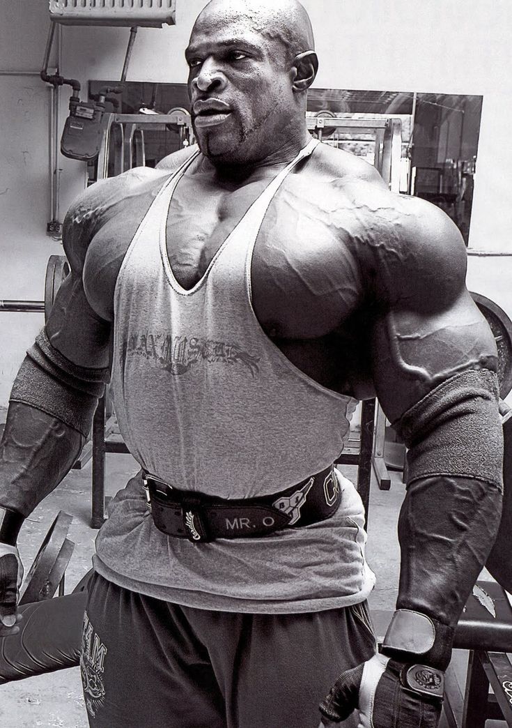 a black and white photo of a man in a gym with his hands on his hips