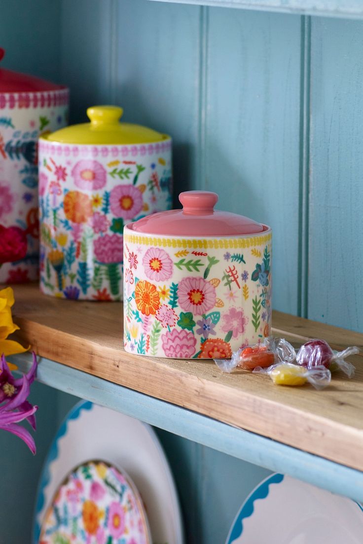 colorful floral canisters and plates on a shelf