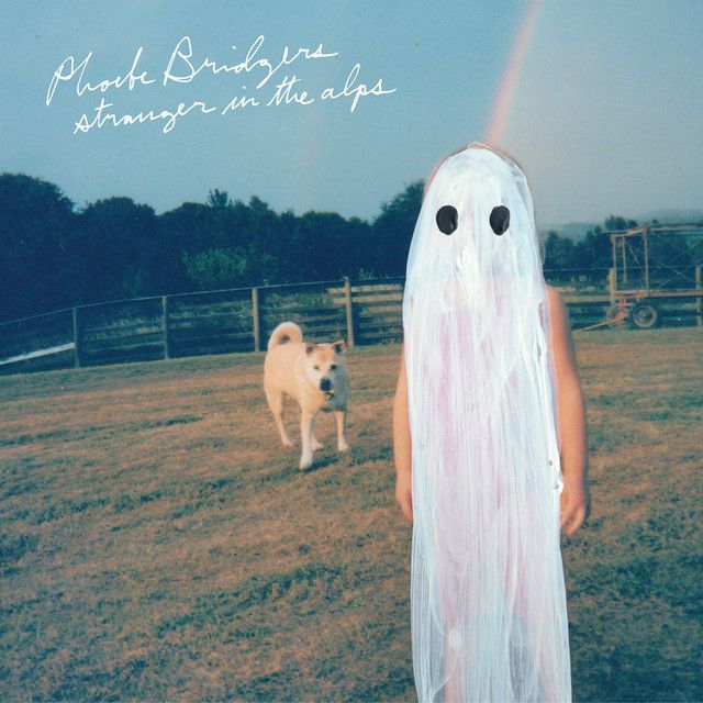 a person in a ghost costume standing next to a dog with a rainbow behind them