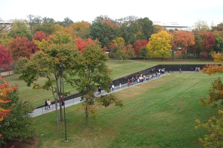 an aerial view of people walking on a path in a park surrounded by trees with fall colors