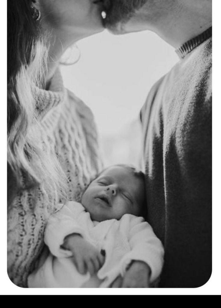 a man and woman kissing while holding a baby