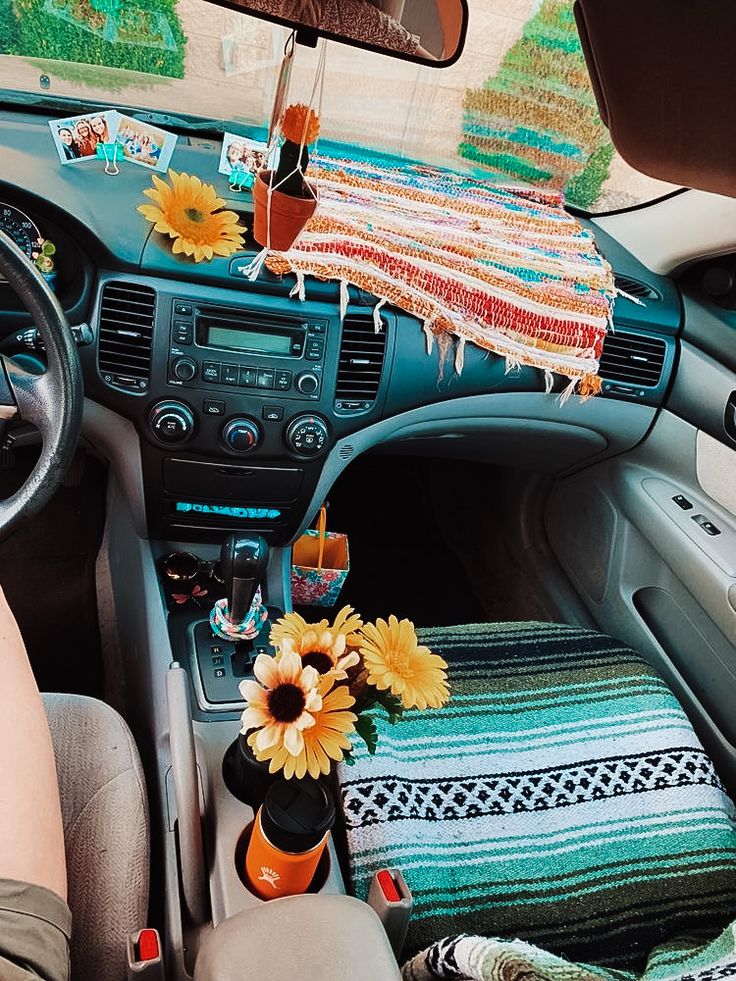 the interior of a car with sunflowers on the dash board and blankets hanging from the ceiling