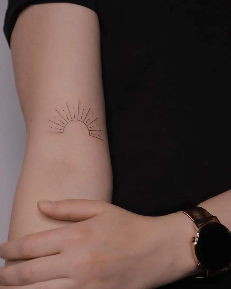 a woman's arm with a small sun tattoo on the left side of her arm