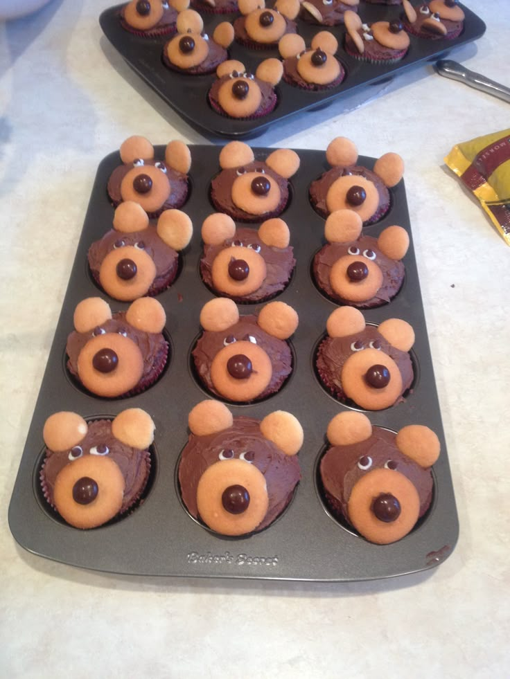 some cupcakes with teddy bears on them sitting in a muffin tin and ready to be eaten