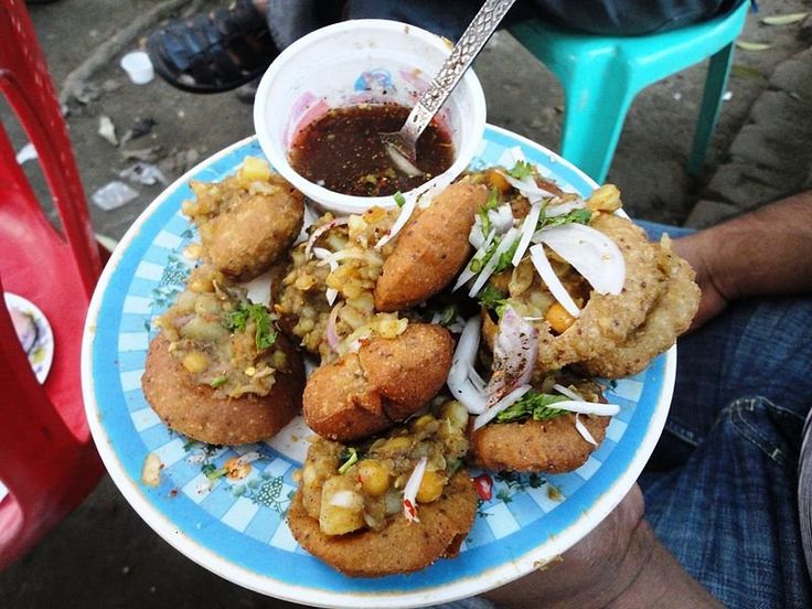 a person holding a plate with fried food on it and dipping sauce in the middle