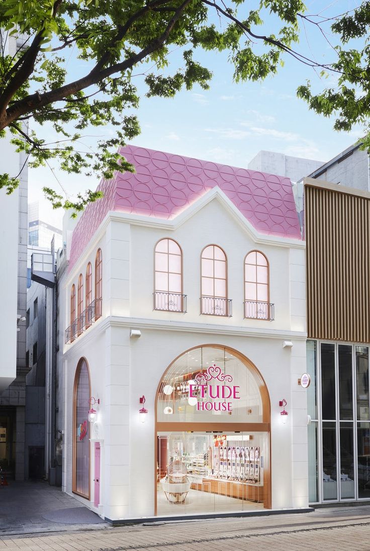 a white building with a pink roof on the side of it's front entrance